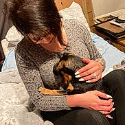 Reese joined the competition — help win amazing prizes! woman, dog, pet, small_dog, manicure, rings, blanket, pillow, bed, cardboard_box, moving_boxes, indoor, sitting, hugging, affection, short_hair, casual_clothing, cute_dog, human_face, animal_face