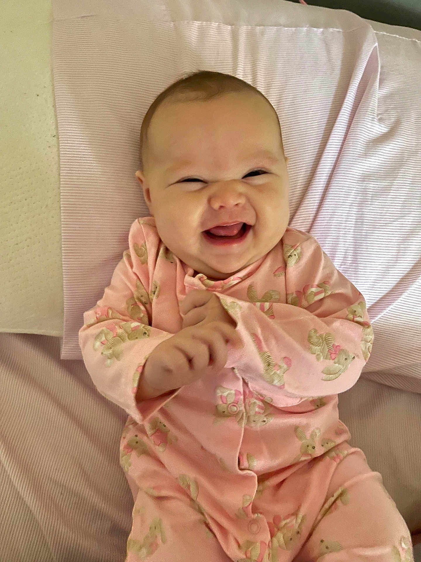 Ariadna Ceslete is registered to the contest to win money with this photo: baby, smiling, laughing, pink_onesie, bunny_print, infant, child, cute, happy, lying_down, blanket, soft_texture, clothing, indoors, portrait, playful, young_child, hands, face, expressive