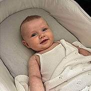 Bonnie is registered to the contest to win money with this photo: baby, bassinet, blanket, child, comfort, cushion, cute, face, happy, indoors, infant, knitted_blanket, portrait, resting, skin, sleeping_area, smile, soft_lighting, white_clothing, young