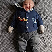 Milo participe au concours pour gagner de l'argent avec cette photo : baby, blue_jacket, casual, child, cozy, cute, face, gray_pants, happy, indoors, infant, lying_down, mittens, newborn, patterned_blanket, person, portrait, smiling, socks, warm_clothing