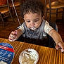 Kaysyn joined the competition — help win amazing prizes! toddler, child, high_chair, whipped_cream, messy_face, table, restaurant, wooden_table, wooden_floor, chair, curly_hair, bib, food, eating, indoor, baby, person, clothing, mess, cute