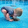 baby, barefoot, blue_background, child, crouching, curiosity, fountain, kneeling, outdoor_play, playground, pool_surface, portrait, short_hair, splash, splashing, striped_shirt, summer, toddler, water, young_child