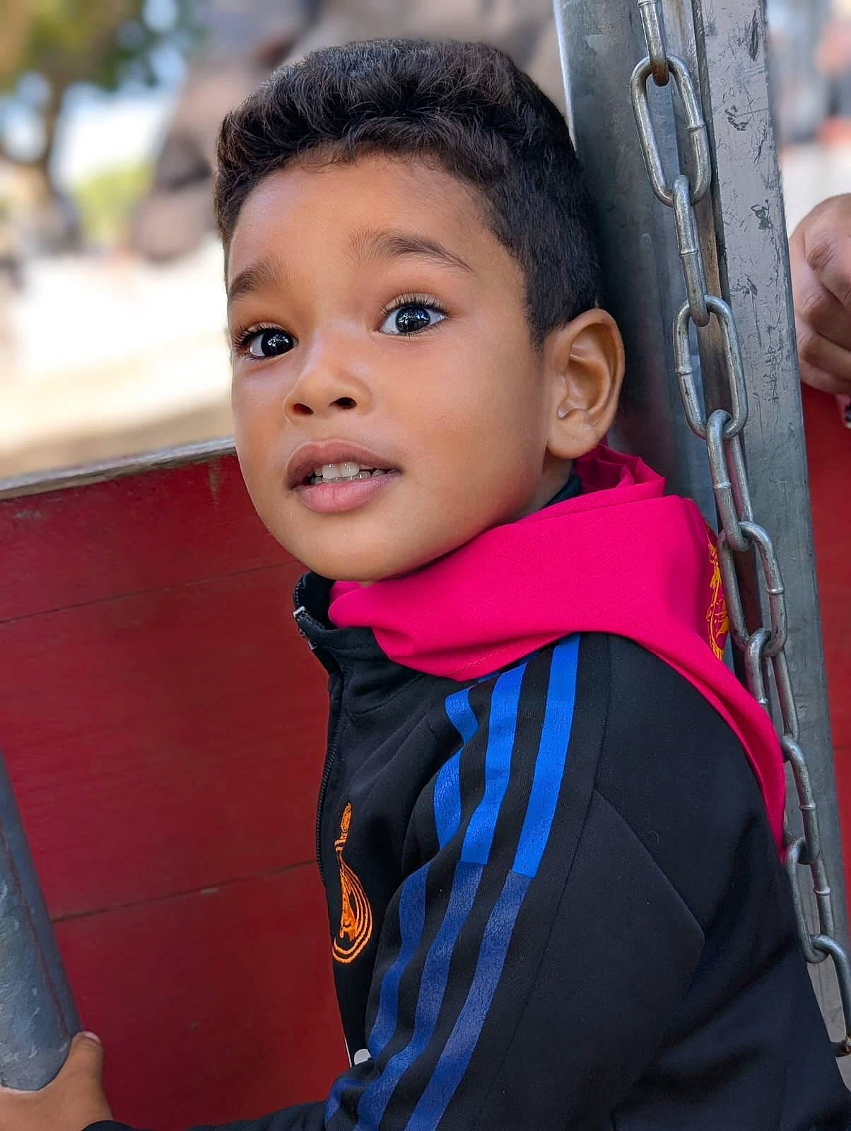Yanis a rejoint le concours — aidez-le/la à gagner de superbes lots ! black_jacket, blue_stripes, boy, casual_clothing, chain, child, closeup, curious, daylight, expression, face, grip, hoodie, metal_pole, outdoor, person, pink_hood, portrait, skin, young