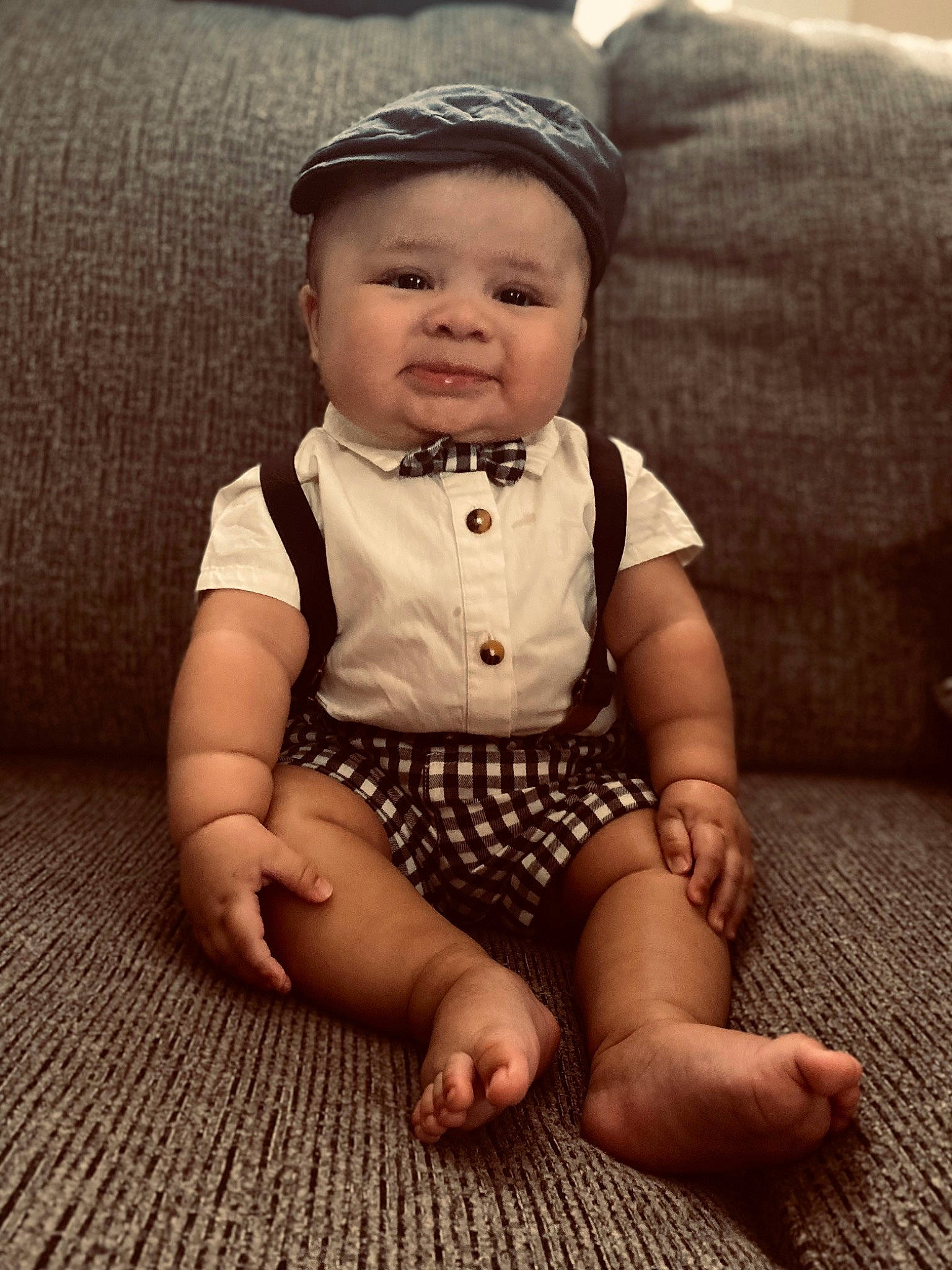 Caspian is registered to the contest to win money with this photo: baby, baby_toddler_clothing, comfort, couch, eye, face, finger, flash_photography, flooring, grass, happy, headwear, human_leg, iris, pattern, person, sitting, skin, sleeve, smile