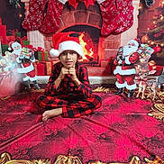 Keylor Jam is registered to the contest to win money with this photo: child, santa_hat, pajamas, christmas_decorations, stockings, fireplace, gifts, red_carpet, holiday, festive, indoor, smiling, pose, cute, holiday_theme, christmas, sitting, celebration, decor, holiday_season