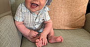 Owen joined the competition — help win amazing prizes! baby, child, smiling, hat, blue_clothing, plaid, armchair, cushion, happy, sitting, indoors, person, face, cute, infant, foot, hand, skin, portrait, cozy