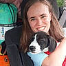 Lily joined the competition — help win amazing prizes! woman, person, puppy, dog, black_and_white, pet, portrait, smiling, teeth, long_hair, car, car_interior, seat, seatbelt, cuddling, holding, closeup, animal, outdoor_background, candid