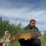 Aïsko participe au concours pour gagner de l'argent avec cette photo : man, dog, fish, grass, reeds, sky, outdoor, nature, fishing, animal, person, water, catch, pet, greenery, clouds, wildlife, summer, hobby, leisure