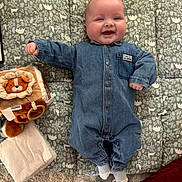 Sacha participe au concours pour gagner de l'argent avec cette photo : baby, denim_onesie, smiling, happy, toy, plush_toy, blanket, patterned_mat, floor, indoor, child, infant, cute, lying_down, cozy, soft_texture, head, feet, socks, portrait
