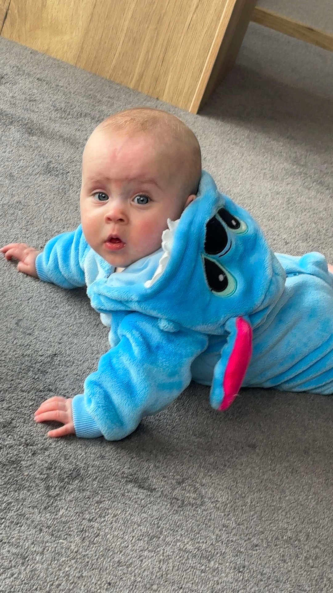Elsie-Mai joined the competition — help win amazing prizes! baby, infant, blue_onesie, hood, carpet, floor, child, cute, indoor, expression, face, eyes, hands, soft_texture, plush, casual, portrait, looking_up, surprised, young