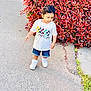 toddler, child, boy, white_shirt, mickey_mouse, denim_shorts, white_sneakers, sidewalk, red_leaves, bush, outdoor, daylight, curious, walking, casual_clothing, nature, greenery, young_child, person, cute