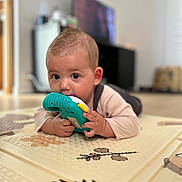 Eden participe au concours pour gagner de l'argent avec cette photo : baby, child, toy, floor_mat, indoor, curious, chewing, patterned_mat, wide_eyes, infant, playtime, soft_focus, hand, head, skin, clothing, room, furniture, background, young