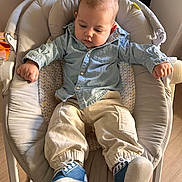 Eden a rejoint le concours — aidez-le/la à gagner de superbes lots ! baby, baby_chair, casual_clothing, child, comfortable, cushion, cute, floor, footwear, indoor, infant, looking_down, pants, person, relaxed, seated, shirt, sneakers, wood_floor, young_child