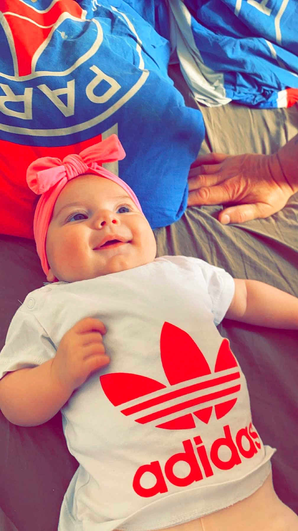 Nelya participe au concours pour gagner de l'argent avec cette photo : baby, smile, headband, pink, shirt, adidas, bed, pillow, hand, infant, clothing, happy, person, lying_down, bright, indoor, cute, resting, child, soft