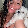 Frankie is registered to the contest to win money with this photo: woman, dog, smile, curly_hair, white_dog, pet, indoor, close_up, happy, affection, portrait, holding, cute, animal, friendship, face, love, companion, skin, black_top