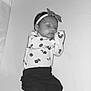 baby, sleeping, headband, bow, pajamas, floral_pattern, infant, peaceful, resting, cute, child, soft_surface, black_and_white, newborn, portrait, lying_down, cozy, indoors, clothing, person