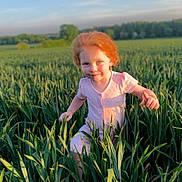 Priscilla is registered to the contest to win money with this photo: child, red_hair, pink_dress, field, greenery, grass, outdoor, sunlight, nature, happy, playful, blue_sky, young_girl, summer, smiling, portrait, daylight, cute, person, environment