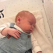 Ysaac participe au concours pour gagner de l'argent avec cette photo : baby, sleeping, infant, crib, blanket, overalls, white_shirt, peaceful, soft_lighting, indoors, face, hand, head, cozy, sleepwear, child, resting, newborn, cute, portrait