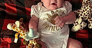 Lemailey is registered to the contest to win money with this photo: baby, black, blanket, checkered, child, cute, flower, giraffe_toy, headband, indoors, infant, lying_down, onesie, pacifier, person, plush_toy, portrait, red, socks, soft_toys