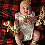 Lemailey is registered to the contest to win money with this photo: baby, black, blanket, checkered, child, cute, flower, giraffe_toy, headband, indoors, infant, lying_down, onesie, pacifier, person, plush_toy, portrait, red, socks, soft_toys