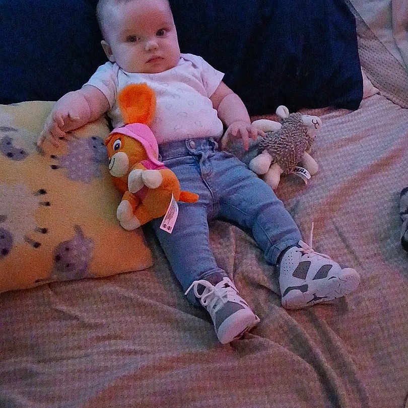 Lemailey is registered to the contest to win money with this photo: baby, bed, blanket, casual_clothing, child, comfort, cuddly_toy, cute, indoor, infant, jeans, person, pillow, plush_toy, relaxed, resting, sneakers, soft_lighting, white_shirt, young_child