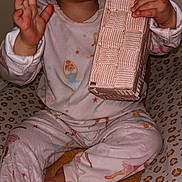 Inaya participe au concours pour gagner de l'argent avec cette photo : toddler, child, pajamas, pink, ballerina_print, blanket, leopard_print, yellow_blanket, indoor, holding_object, textured_object, curious, sitting, barefoot, face, earrings, long_sleeve, cozy, cute, portrait