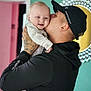 baby, man, kiss, smile, tattoo, cap, under_armour, onesie, indoor, wall, doorway, colorful_background, affection, family, love, holding, portrait, happy, person, head