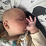 baby, sleeping, thumb_sucking, infant, pillow, patterned_clothing, animal_print, closeup, peaceful, resting, cute, child, soft_lighting, indoors, portrait, toddler, cozy, face, hand, apparel