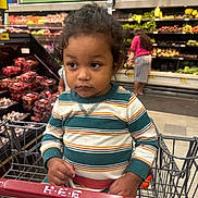 Hector joined the competition — help win amazing prizes! child, toddler, baby, portrait, shopping_cart, supermarket, grocery_store, produce, vegetables, fruit, sitting, curly_hair, striped_shirt, facial_expression, indoors, shopping, cart, store_aisle, background_shopper, family_outing