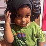 Hector joined the competition — help win amazing prizes! child, toddler, portrait, face, indoor, sitting, bonnet, hat, black_hat, green_shirt, dinosaur, clothing, hand, curious, serious_expression, brown_eyes, close_up, furniture, home, photography