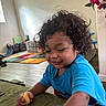 toddler, child, curly_hair, blue_shirt, sitting, couch, snack, food, indoor, home, playroom, play_mat, flowers, bougainvillea, portrait, face, person, looking_down, natural_light, happy