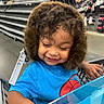 Hector is registered to the contest to win money with this photo: child, toddler, smiling, shopping, shopping_cart, store, shoe_store, earmuffs, fluffy, blue_shirt, superhero_shirt, gift_bag, colorful, portrait, indoors, retail, shelves, shoes, happy, family