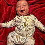 baby, infant, smiling, onesie, winnie_the_pooh, blanket, red_blanket, dimples, happy, cute, child, sleepwear, lying_down, soft_texture, face, apparel, young_child, indoors, comfort, joy