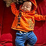 Kingstyn is registered to the contest to win money with this photo: baby, blue_pants, casual_wear, child, clothing, comfort, couch, cute, home, indoor, infant, orange_hoodie, orange_socks, pillow, portrait, red_fabric, relaxing, resting, sleeping, tigger