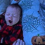 baby, yawning, infant, hand, rings, blanket, spider_web, jack_o_lantern, halloween, red_clothing, black_clothing, plaid, sleepy, cute, lying_down, indoor, person, child, cozy, soft