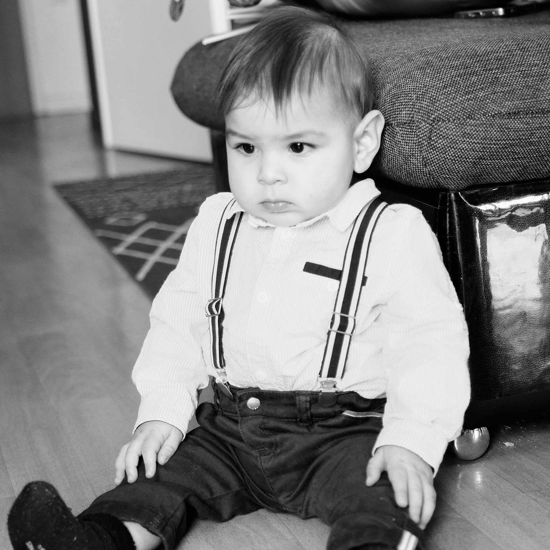 Naël a rejoint le concours — aidez-le/la à gagner de superbes lots ! black_and_white, child, couch, cute, expression, feet, floor, hands, home, indoor, living_room, pants, person, portrait, rug, shirt, sitting, suspenders, toddler, young_child