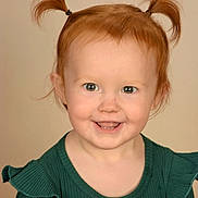 Adalyne is registered to the contest to win money with this photo: toddler, child, red_hair, pigtails, smiling, green_top, portrait, cute, baby, face, happy, young_child, sitting, indoor, person, ribbons, button, light_background, studio, fashion