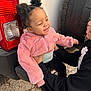 Naomi is registered to the contest to win money with this photo: toddler, child, person, pink_jacket, curly_hair, pigtails, sneakers, vehicle, car_tire, tail_light, outdoor, pavement, smiling, holding, playful, casual_clothing, joyful, interaction, daylight, candid