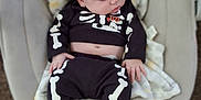 Charles joined the competition — help win amazing prizes! baby, sleeping, infant, clothing, skeleton_outfit, blanket, baby_seat, cozy, indoors, person, cute, soft_toys, striped_socks, black_clothing, white_bones, red_socks, peaceful, portrait, child, resting
