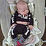 baby, sleeping, infant, clothing, skeleton_outfit, blanket, baby_seat, cozy, indoors, person, cute, soft_toys, striped_socks, black_clothing, white_bones, red_socks, peaceful, portrait, child, resting