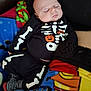 Charles is registered to the contest to win money with this photo: baby, sleeping, infant, halloween, skeleton_costume, pumpkin, clothing, striped_socks, blanket, colorful, cute, child, young, lying_down, peaceful, face, portrait, soft_lighting, indoors, cozy