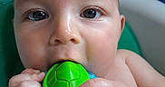 Jayce is registered to the contest to win money with this photo: baby, infant, child, face, eyes, hands, teething_toy, toy, green, blue, portrait, close_up, indoor, seated, curious, looking_at_camera, bare_arms, soft_lighting, home, photography