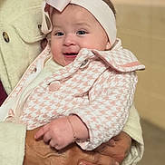 Ariathna is registered to the contest to win money with this photo: adult_hands, baby, blurred_background, bokeh, bow, bracelet, cheeks, coat, earring, fire_extinguisher, hands, headband, holding, houndstooth, indoor, infant, pink, portrait, ring, smile