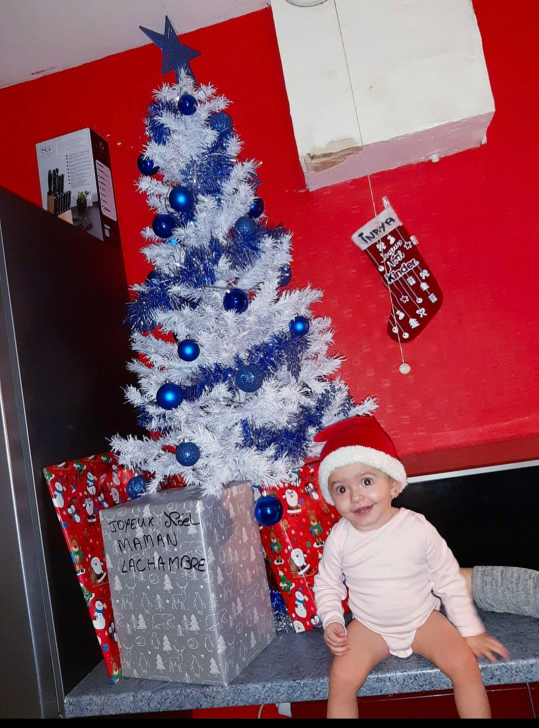 Inaya participe au concours pour gagner de l'argent avec cette photo : baby, baby_toddler_clothing, christmas, christmas_decoration, christmas_eve, christmas_lights, christmas_ornament, christmas_tree, conifer, event, fir, headwear, holiday, holiday_ornament, interior_design, joy, office_equipment, ornament, person, pine_family