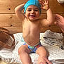Lylian a rejoint le concours — aidez-le/la à gagner de superbes lots ! adult_hand, baby, bag, bare_chest, casual, changing_pad, child, clothing, fabric, hand, happy, indoor, person, shorts, skin, smile, swim_cap, table, toddler, wooden_wall