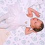 newborn, baby, infant, sleeping, white_clothing, tights, blanket, plush_toy, patterned_blanket, soft_texture, cute, peaceful, lying_down, indoors, baby_girl, small_heart, embroidery, decorative, pastel_colors, baby_accessory