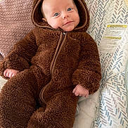 Wren is registered to the contest to win money with this photo: baby, child, onesie, brown, fluffy, cushion, patterned, smile, face, head, infant, clothing, cute, comfort, indoor, portrait, soft, relax, young, hood