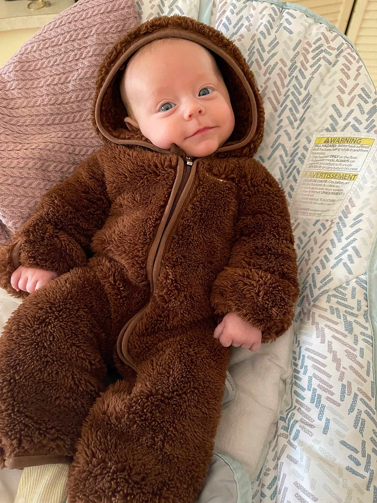 Wren is registered to the contest to win money with this photo: baby, child, onesie, brown, fluffy, cushion, patterned, smile, face, head, infant, clothing, cute, comfort, indoor, portrait, soft, relax, young, hood