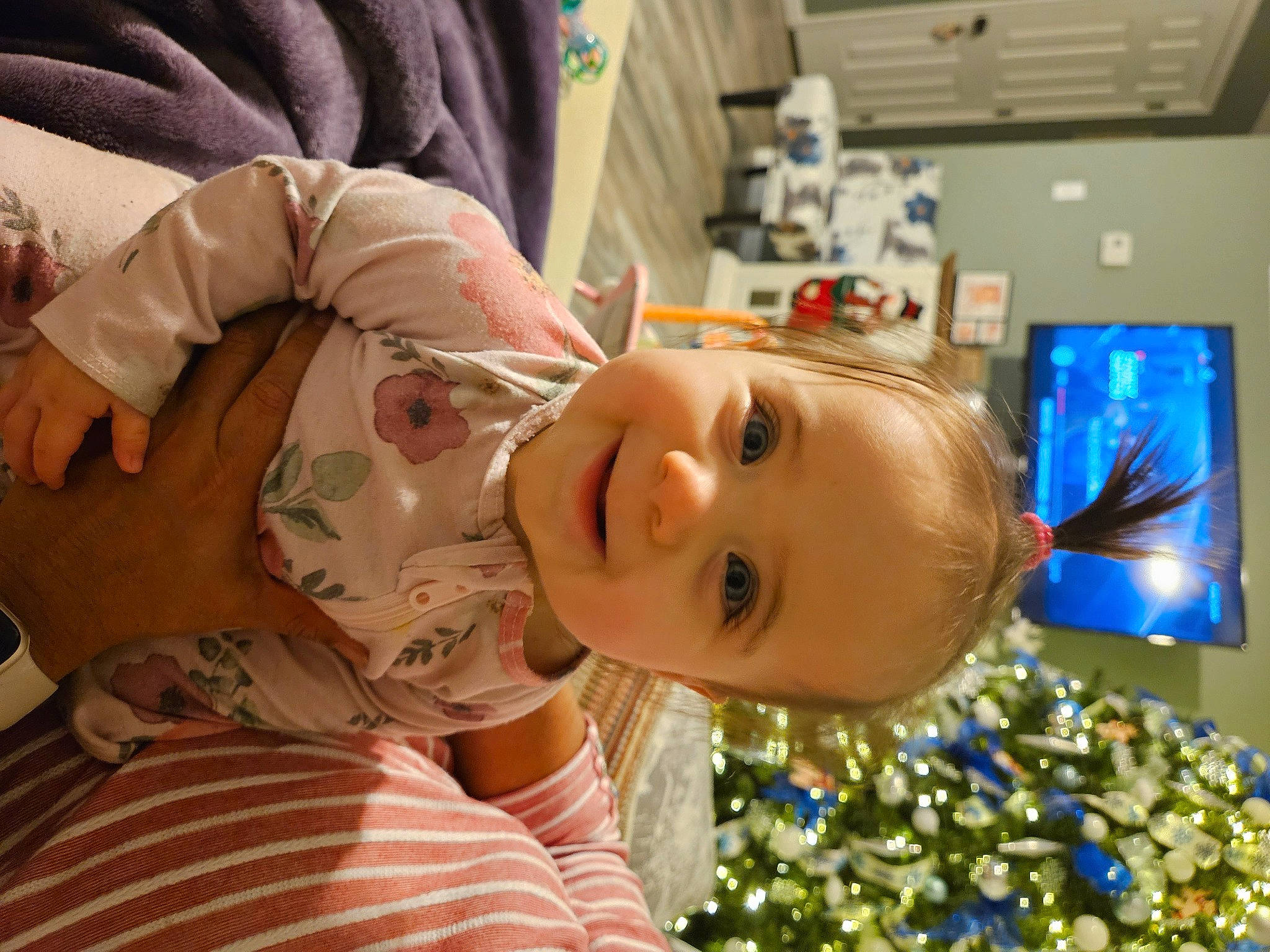 Penelope is registered to the contest to win money with this photo: baby, cheek, child, christmas, christmas_decoration, christmas_eve, christmas_ornament, christmas_tree, display_device, event, eyelash, fun, happy, holiday, joy, leisure, ornament, person, room, television