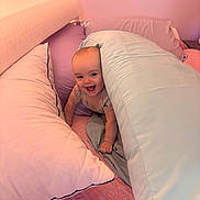 Olivia is registered to the contest to win money with this photo: baby, pillow, bed, blanket, smile, happy, infant, indoor, child, face, head, cute, cozy, pink, quilt, cushion, playful, person, young, rest